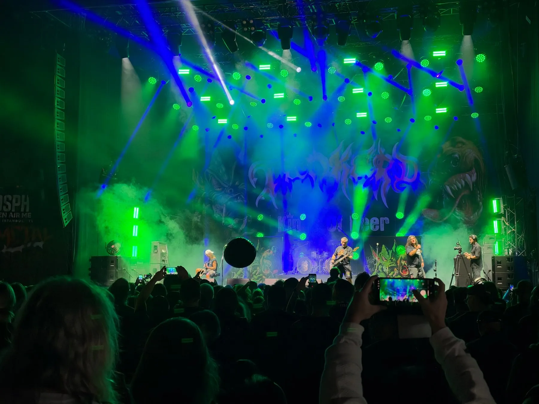 Tankard on stage beneath green and blue lights, viewed from the crowd
