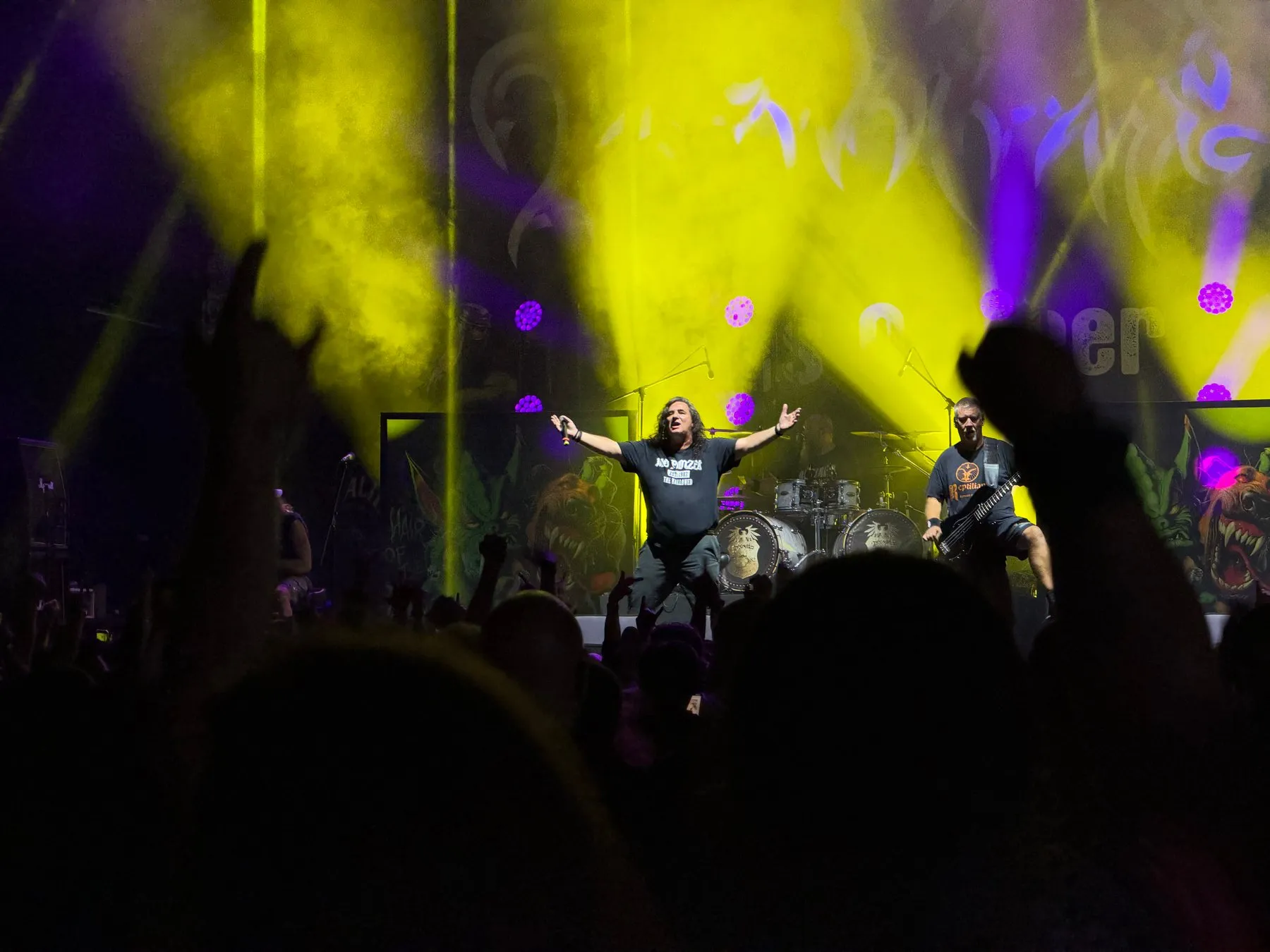 Tankard's singer with his arms raised beneath yellow lights